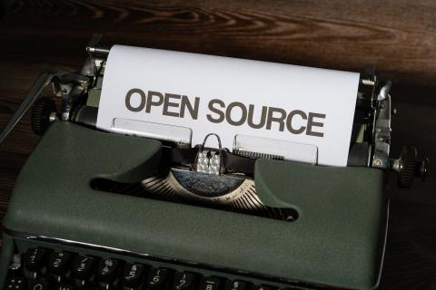 Starinski pisalni stroj v katerem je papir z angleškim napisom "open source".